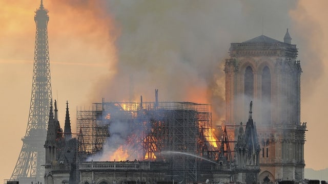 Die Notre-Dame Kathedrale in Paris steht in Flammen mit viel Rauch oberhalb.
