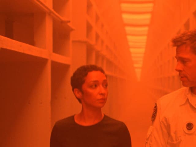 Brad Pitt und Ruth Negga in einem Gang, der orange beleuchtet ist. Brad Pitt und Ruth Negga in einem Gang, der orange beleuchtet ist.