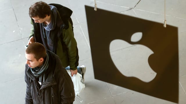 Personen gehen an einem Apple-Logo vorbei. Personen gehen an einem Apple-Logo vorbei.