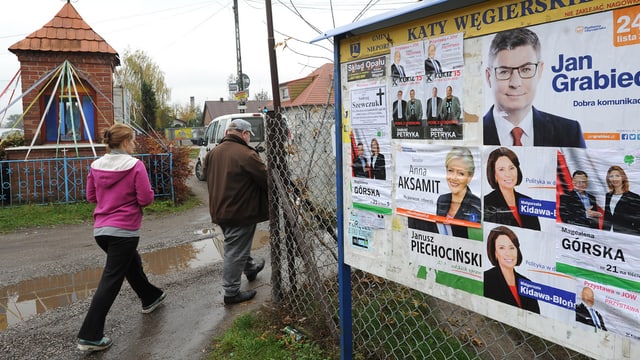 Zwei Personen laufen an Wahlplakaten vorbei Zwei Personen laufen an Wahlplakaten vorbei