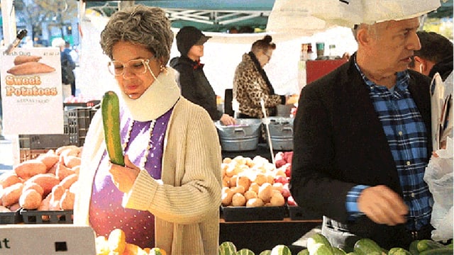 Frau prüft Gurke am Marktstand Frau prüft Gurke am Marktstand