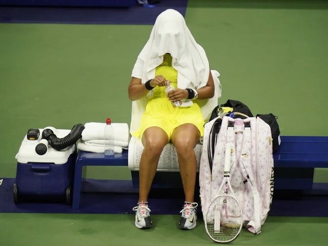 Naomi Osaka vergräbt sich auf dem Court unter einem Handtuch. Naomi Osaka vergräbt sich auf dem Court unter einem Handtuch.