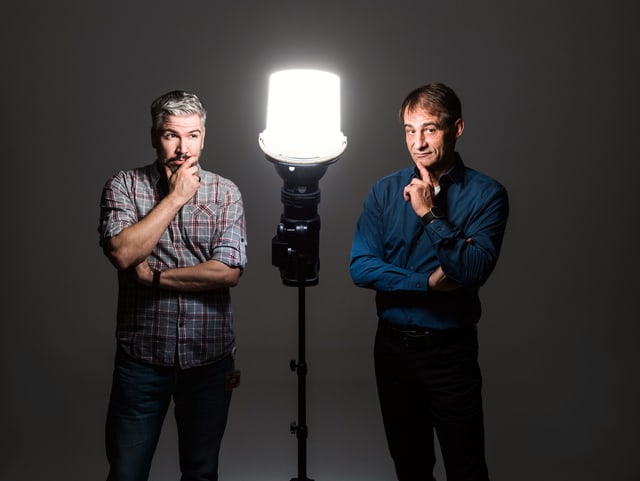 Thomy Scherrer und Krispin Zimmerman stehen in der Dunkelheit vor einem einzigen erleuchteten Scheinwerfer und blicken in die Kamera. Thomy Scherrer und Krispin Zimmerman stehen in der Dunkelheit vor einem einzigen erleuchteten Scheinwerfer und blicken in die Kamera.