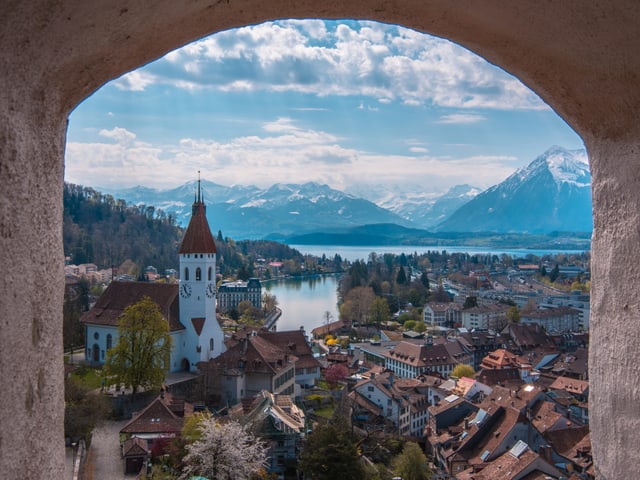 Blick aus einem Steinfenster auf Altstadt mit See. Leicht bewölkter Himmel, sonst sonnig.