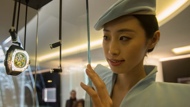 Chinesin betrachtet teure Uhr in der Auslage eines Geschäfts Chinesin betrachtet teure Uhr in der Auslage eines Geschäfts