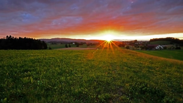Die untergehende Sonne verfärbt die Wolken am Himmel rötlich. Die untergehende Sonne verfärbt die Wolken am Himmel rötlich.