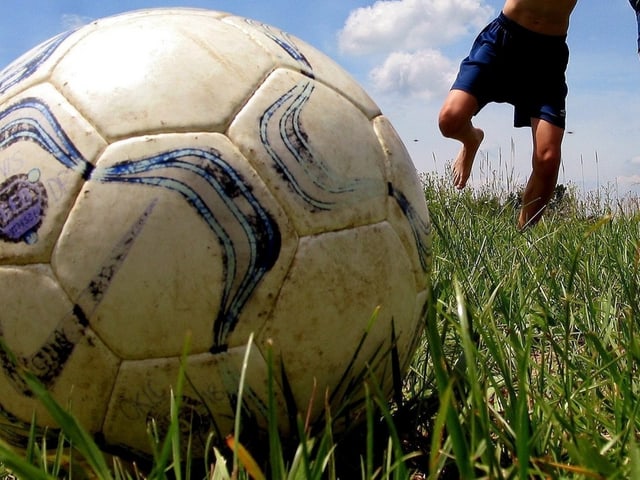 Zwei Kinder rennen auf einen Fussball zu. Zwei Kinder rennen auf einen Fussball zu.