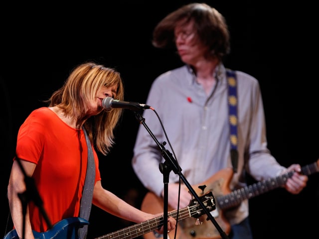 Im Vordergrund steht Kim Gordon am Mikrofon, im Hintergrund Thurston Moore. Im Vordergrund steht Kim Gordon am Mikrofon, im Hintergrund Thurston Moore.