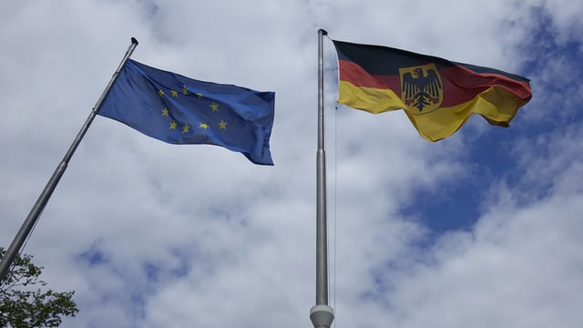 Symbolbild: EU- und deutsche Flagge wehen an je einem Fahnenmast. Symbolbild: EU- und deutsche Flagge wehen an je einem Fahnenmast.