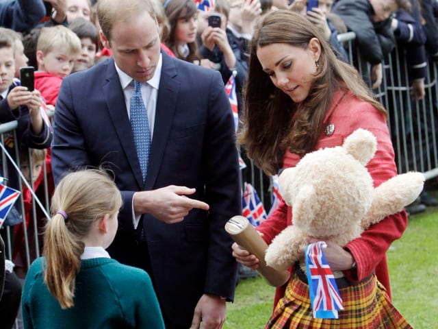 Kate und William nehmen den Schotten-Bär für ihren Sohn entgegen. Davor steht ein Mädchen mit grünem Pulli. Kate und William nehmen den Schotten-Bär für ihren Sohn entgegen. Davor steht ein Mädchen mit grünem Pulli.