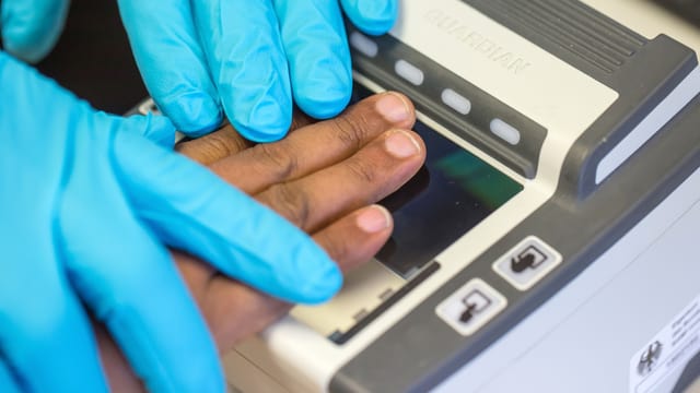Ein Integrationsbeauftragter nimmt in einem Erstaufnahmezentrum Fingerabdrücke von einem Flüchtling. Ein Integrationsbeauftragter nimmt in einem Erstaufnahmezentrum Fingerabdrücke von einem Flüchtling.
