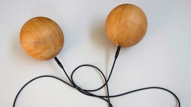 Zwei Holzkugeln, die mit einem Gitarrenkabel verbunden sind. Zwei Holzkugeln, die mit einem Gitarrenkabel verbunden sind.