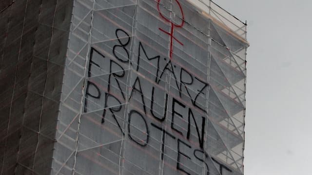 Das eingerüstete Fraumünster mit einem Protest-Schriftzug. Das eingerüstete Fraumünster mit einem Protest-Schriftzug.