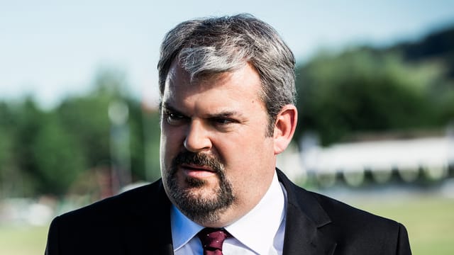 Müller als Luc Conrad im Anzug mit Krawatte. Müller als Luc Conrad im Anzug mit Krawatte.