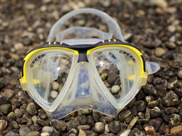 Eine Taucherbrille liegt auf einem Kiesboden. Eine Taucherbrille liegt auf einem Kiesboden.