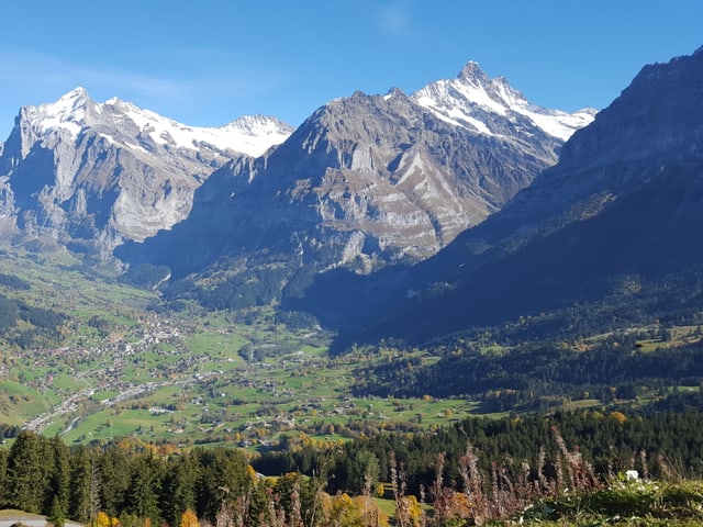 Im Hintergrund Schneeberge, im Vordergrund ein Dorf auf grünen Wiesen. Im Hintergrund Schneeberge, im Vordergrund ein Dorf auf grünen Wiesen.