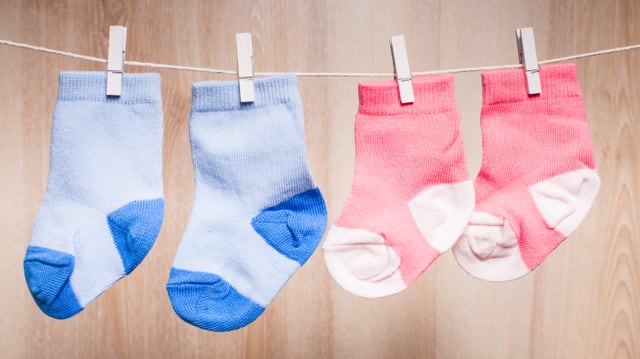 Ein Paar blaue und ein Paar rosa Socken hängen an einer Wäscheleine. Ein Paar blaue und ein Paar rosa Socken hängen an einer Wäscheleine.