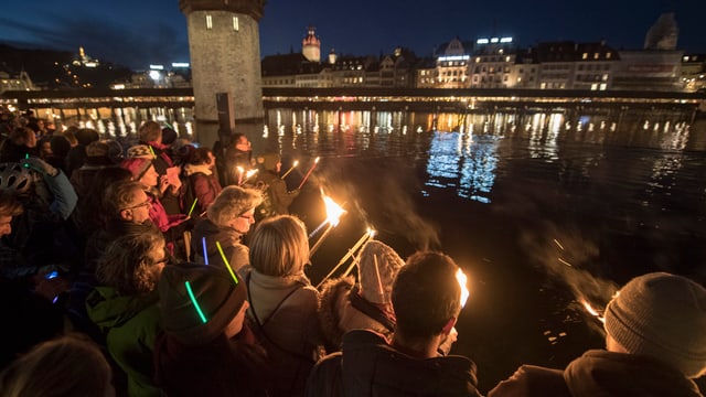 Menschen mit Fackeln, im Hintergrund die Kappelbrücke. Menschen mit Fackeln, im Hintergrund die Kappelbrücke.