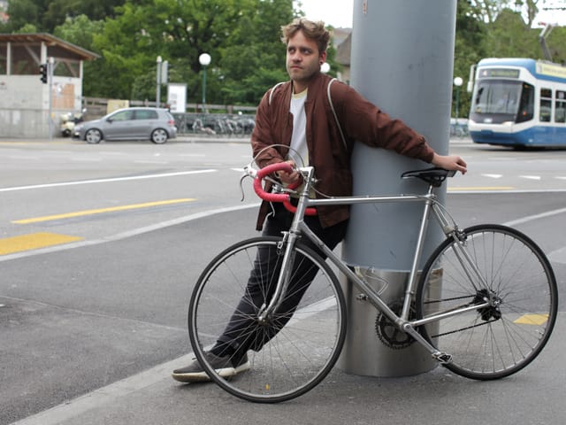 Amir posiert mit seinem Fahrad an einer Säule.
