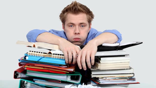 Ein Mann schaut frustriert und stützt sich auf Bücher Ein Mann schaut frustriert und stützt sich auf Bücher