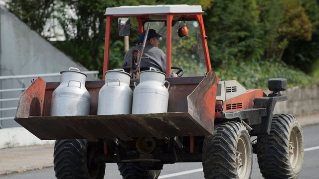 Ein Bauer transportiert Milchkannen mit dem Traktor. Ein Bauer transportiert Milchkannen mit dem Traktor.