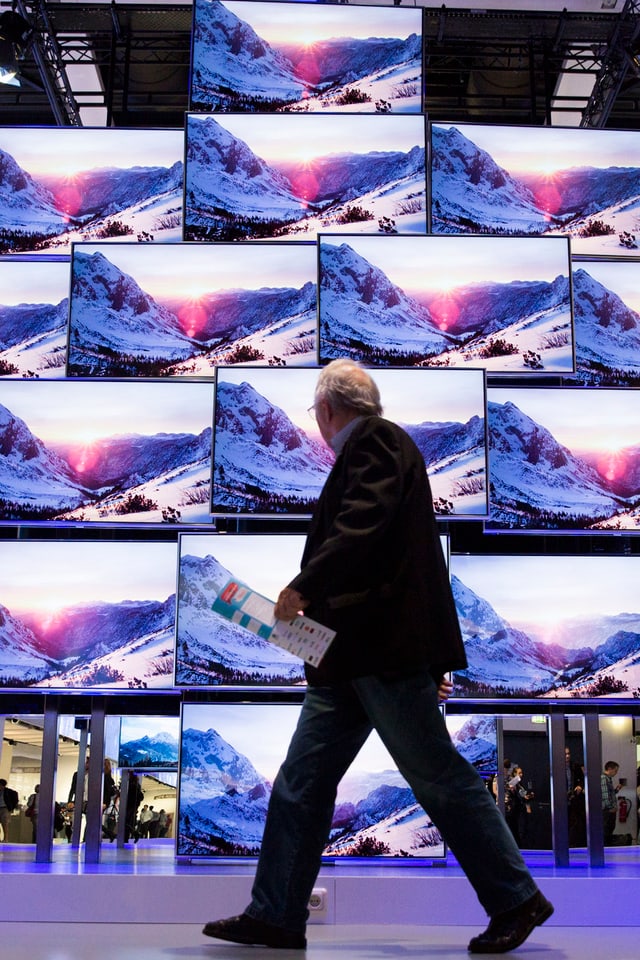 Mann vor Wand aus Fernsehern Mann vor Wand aus Fernsehern