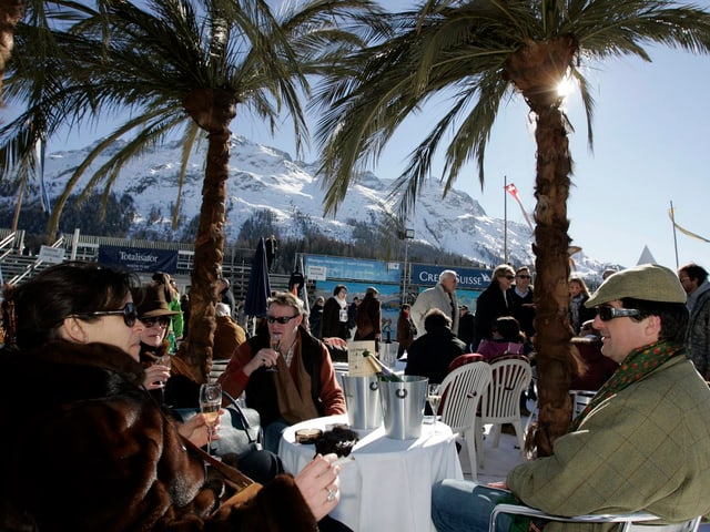 Menschen unter Palmen auf zugefrorenem See in St. Moritz Menschen unter Palmen auf zugefrorenem See in St. Moritz