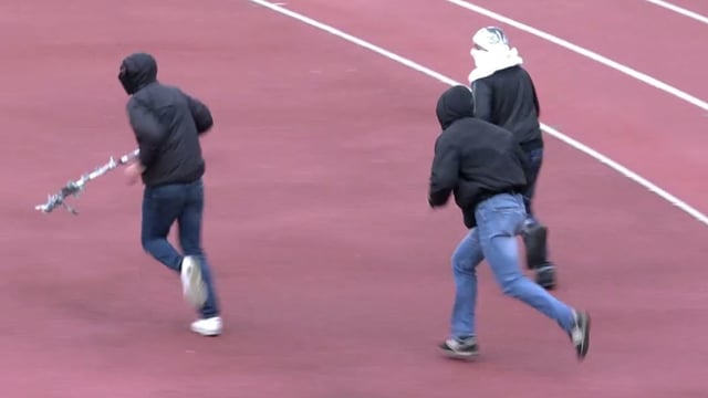 Hooligans rennen über die Tartanbahn im Fussballstadion. Hooligans rennen über die Tartanbahn im Fussballstadion.