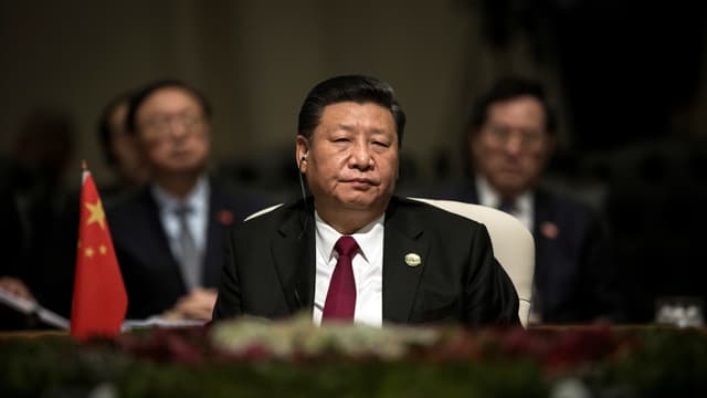 Xi sitzt an einem Tisch, neben ihm eine chinesische Tischflagge. Xi sitzt an einem Tisch, neben ihm eine chinesische Tischflagge.