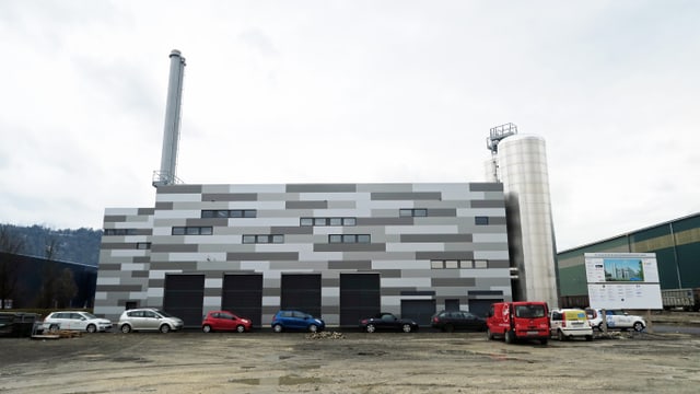 Ein dunkles Industriegebäude mit einem hohen Kamin auf der linken Seite. Ein dunkles Industriegebäude mit einem hohen Kamin auf der linken Seite.