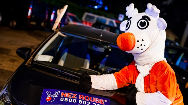 Ein Maskotchen steht vor einem Auto Ein Maskotchen steht vor einem Auto