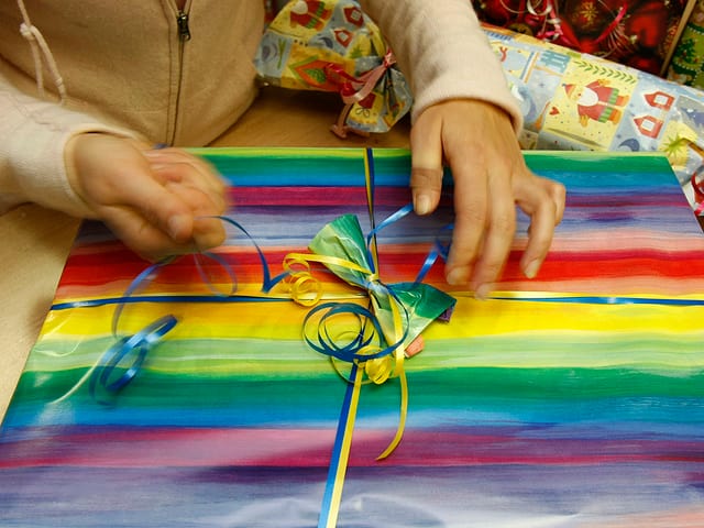 EIn Kind packt ein farbig bepacktes Geschenk aus. EIn Kind packt ein farbig bepacktes Geschenk aus.