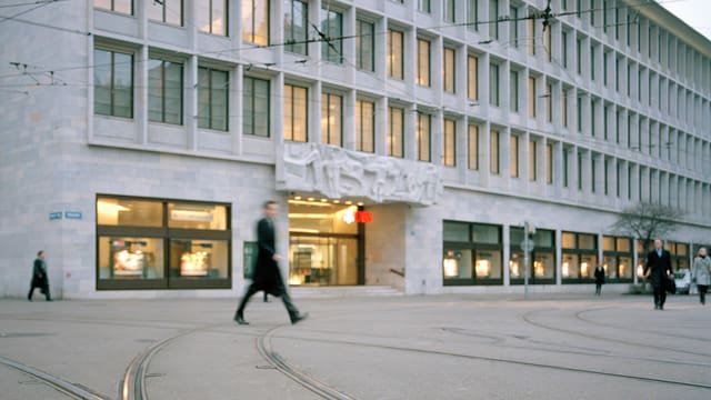 Einige schwarz gekleidete Menschen gehen über den Paradeplatz in Zürich. Einige schwarz gekleidete Menschen gehen über den Paradeplatz in Zürich.