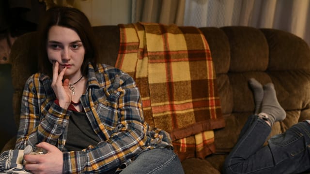 Junge Frau sitzt mit glasigen Augen auf dem Sofa Junge Frau sitzt mit glasigen Augen auf dem Sofa