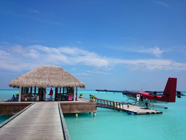 Blick auf einen Steg und eine Hütte in türkisblauem Meer. Ein kleiner Privatflieger ist eben gelandet. Blick auf einen Steg und eine Hütte in türkisblauem Meer. Ein kleiner Privatflieger ist eben gelandet.