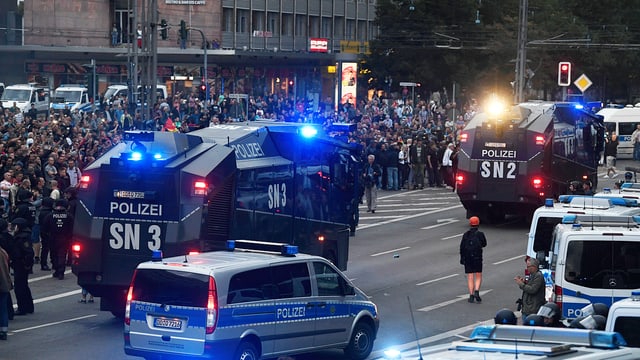 Polizeiautos vor Demonstranten Polizeiautos vor Demonstranten