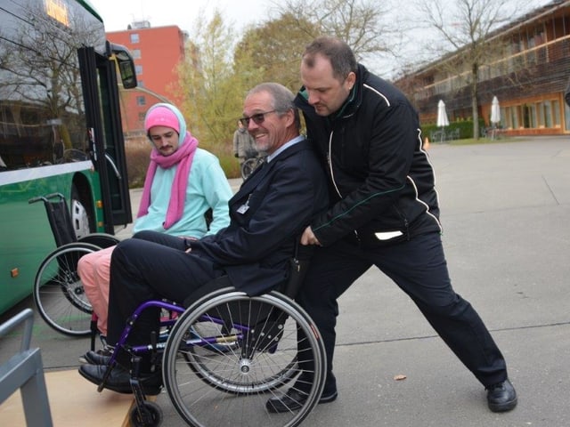 Mann schiebt Rollstuhlfahrer in den Bus