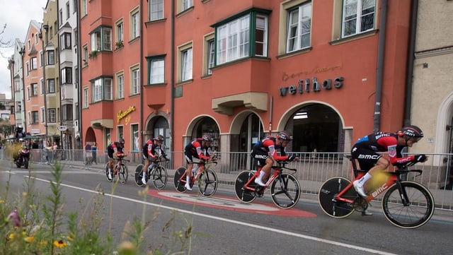 Fünf Velofahrer in rot-schwarzen Trikots fahren durch Innsbruck. Fünf Velofahrer in rot-schwarzen Trikots fahren durch Innsbruck.
