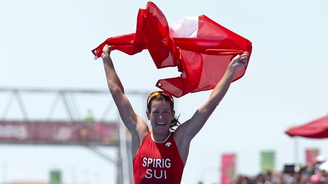 Nicola Spirig läuft jubelnd mit der Schweizer Fahne ins Ziel.
