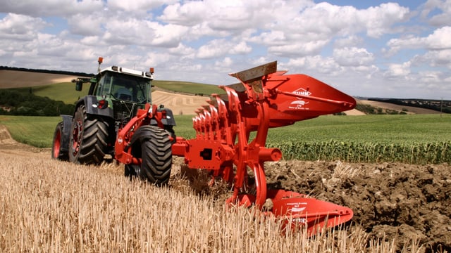 Ein Traktor zieht einen Mehrscharen-Pflug über ein abgeerntetes Getreidefeld.