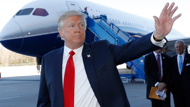 Donald Trump winkend vor einem Boeing-Flugzeug