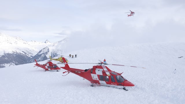 Zwei rot-weisse Rega-Helikopter auf einem Schneefeld. Zwei rot-weisse Rega-Helikopter auf einem Schneefeld.