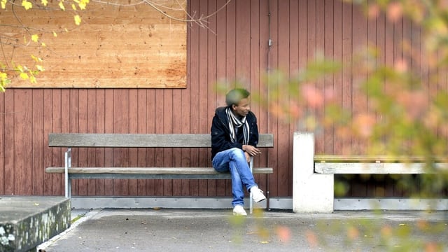 Ein Mann sitzt auf einer Bank vor einer Holzhütte. Ein Mann sitzt auf einer Bank vor einer Holzhütte.