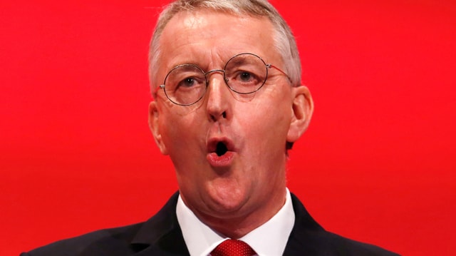 Hilary Benn spricht vor rotem Hintergrund. Hilary Benn spricht vor rotem Hintergrund.
