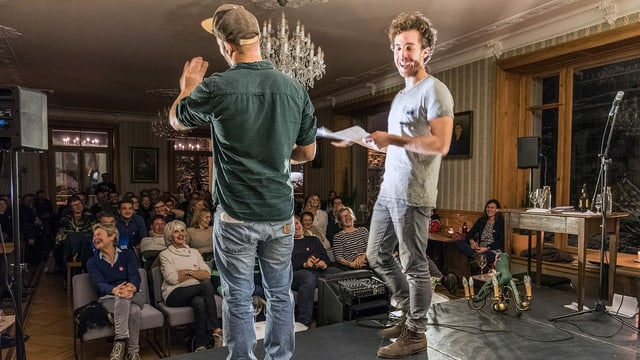 Zwei Männer stehen auf der Bühne - Publikum lacht Zwei Männer stehen auf der Bühne - Publikum lacht