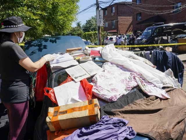 Belongings are left out on the street to dry while police officers and a coroner's team retrieve bodies from a basement apartment. 
