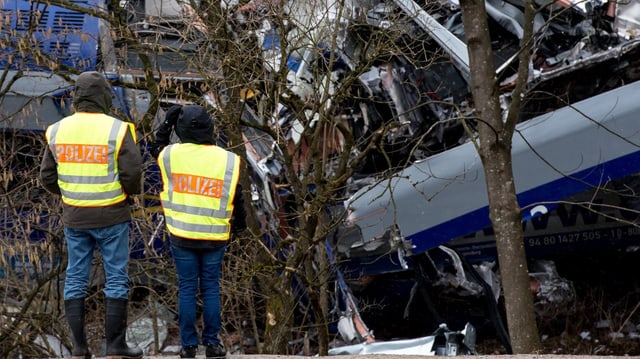 Zwei Beamte mit Leuchtweseten vor den Wracks. Zwei Beamte mit Leuchtweseten vor den Wracks.
