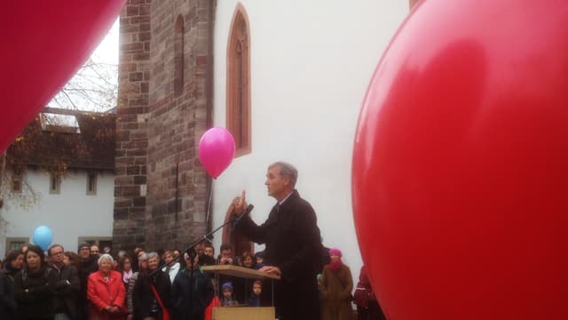 Guy Morin am Rednerpult und rote Ballons