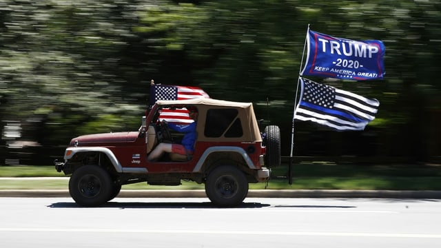 Mann in Auto mit Trump-Fahne Mann in Auto mit Trump-Fahne