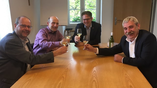 Vier Männer trinken Weisswein an einem Tisch Vier Männer trinken Weisswein an einem Tisch